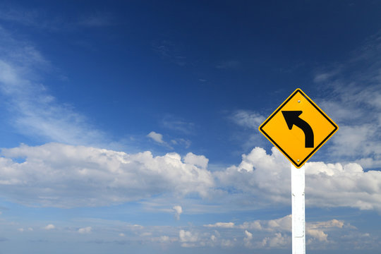 Direction sign- left turn warning on blue sky background