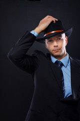 Portrait of handsome man posing on black background in hat