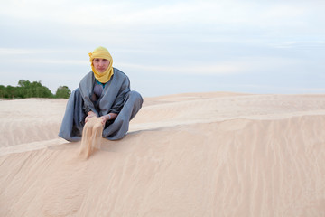 Fototapeta na wymiar Człowiek w ubraniu wschodnich zalewania przez ręce na piasku pustyni