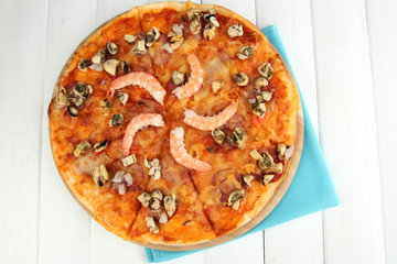 Delicious pizza with seafood on stand on wooden background