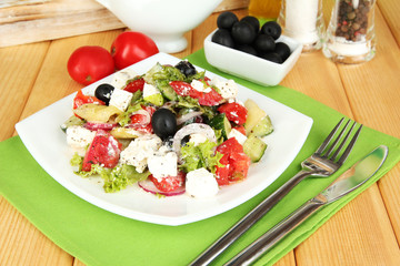 Fresh greek salad on plate on wooden table close-up