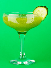 Green vegetable juice in coctail glass on green background