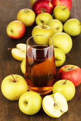 Useful apple juice with apples around on wooden table