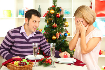 Young happy couple with presents sitting   at table near