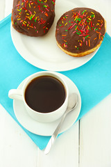 Tasty donuts on color plate on light wooden background