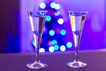 Two glasses of vodka with blurry christmas tree background