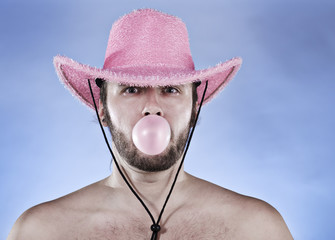 Cowboy in pink hat blowing a gumball.