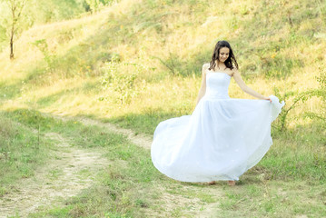 Fototapeta na wymiar Young beautiful bride on green lawn passage
