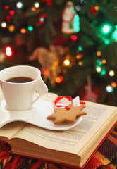 Cup of coffee and cookie near Christmas tree