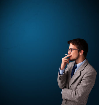 Young man smoking cigarette with copy space