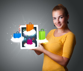 woman holding modern tablet with colorful shopping bags on cloud