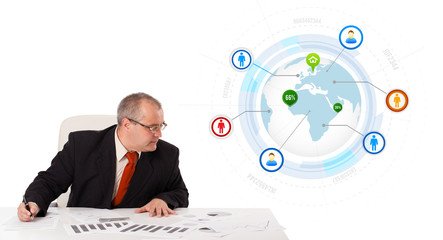 businessman sitting at desk with a globe and social icons