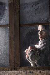 Girl behind window with a cup of coffee or tea