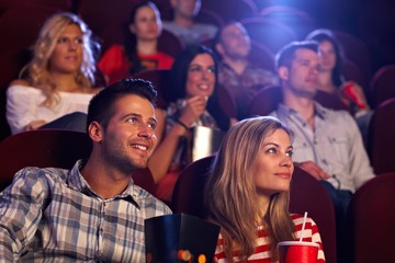 Young people sitting at movie theater - obrazy, fototapety, plakaty