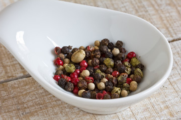 Mixed pepper in bowl on wooden background