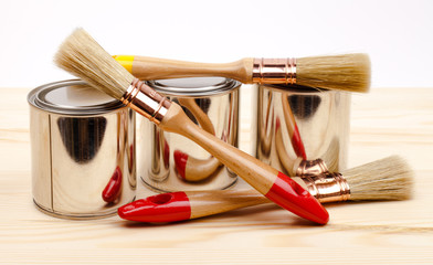 Cans of paint with paintbrushes  on wooden table