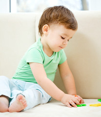 Fototapeta premium Boy is playing while sitting on couch