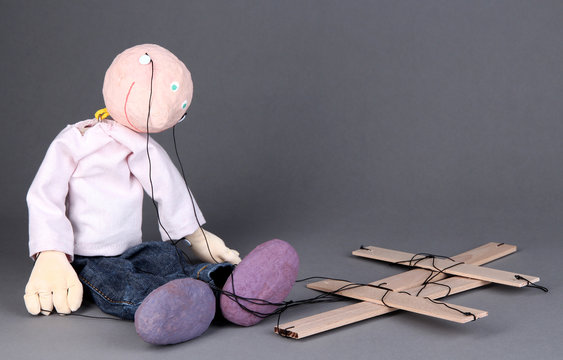 Wooden puppet sitting on grey background