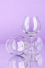 Two empty wine glasses on color background