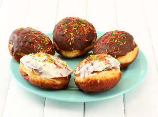 Tasty donuts on color plate on light wooden background