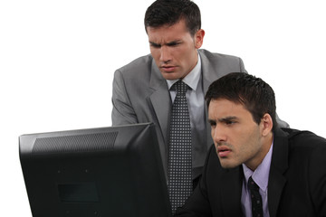 Two serious businessman concentrating on laptop screen