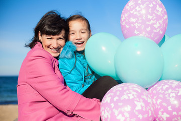 Mom and daughter posing on the beach in autumn with a balloons