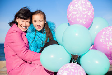 Fototapeta na wymiar Mama i córka pozowanie na plaży w jesieni z balonami