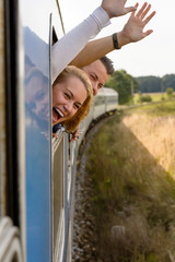 Couple screaming out train window waving happy