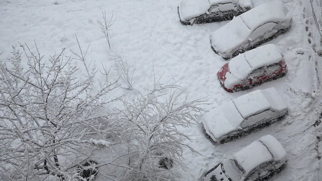 Snow covered cars at the parking lot and snowfall
