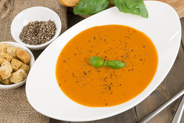 Cream of tomato soup with pepper, basil leaves and croutons.