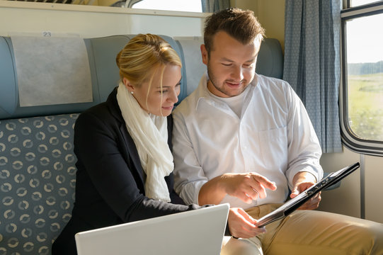 Woman and man in train laptop clipboard