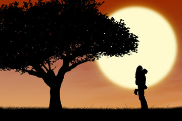 Couple hugging by a tree on orange silhouette sunset