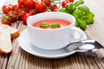 Frische tomatensuppe in einer weißen suppentasse mit basilikum