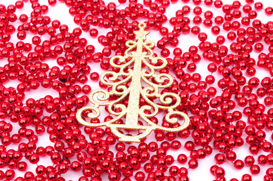 Gold Christmas tree decoration on red beads, isolated on white