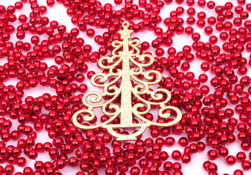 Gold Christmas tree decoration on red beads, isolated on white
