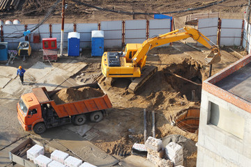 Fototapeta premium Excavator digs hole at construction site.