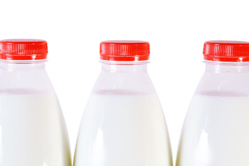 Part of three bottles of milk with red cap isolated on white