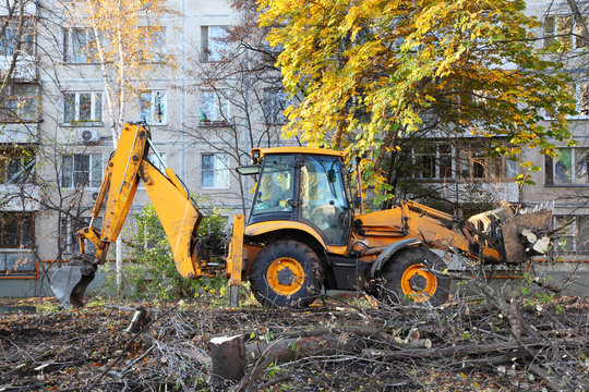 Bulldozer Removes Felled Trees Near Apartment Building