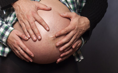 Hands of father holding a belly of pregnant woman