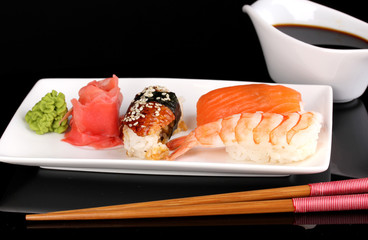 delicious sushi served on plate isolated on black