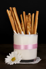 Tasty crispy sticks in glass with sour cream isolated on black