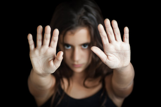 Serious hispanic girl signaling to stop isolated on black