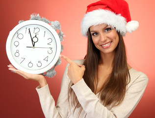 beautiful young woman with clock, on red background