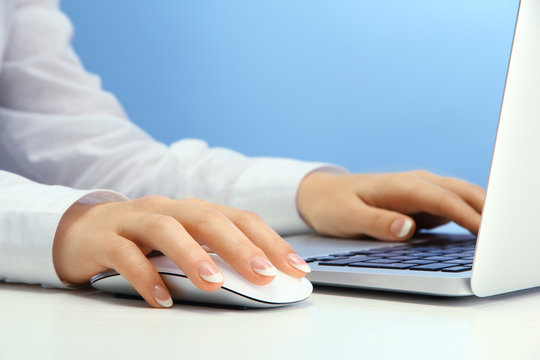female hands writing on laptot, on blue background