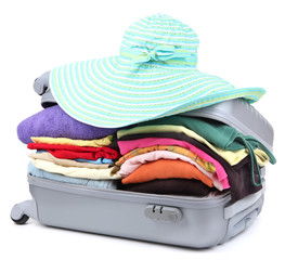Closed silver suitcase with clothing isolated on white