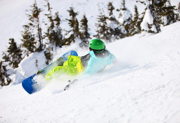 Young male snowboarder after falling on a mountain slope