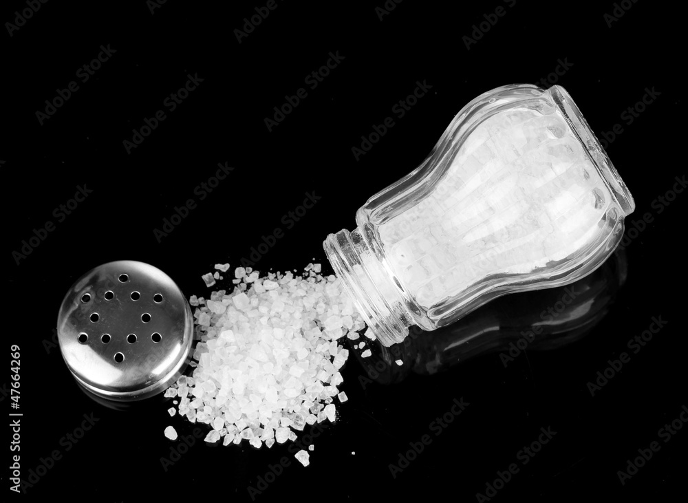 Wall mural salt shaker with spilled salt isolated on black