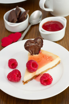cheesecake with raspberries and chocolate heart on the plate