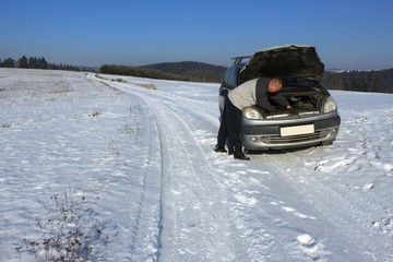 Obraz na płótnie Canvas man repairing the car on a deserted road, winter weather