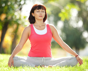 Pretty woman meditate in the park